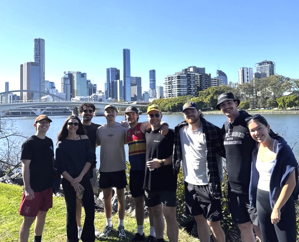 The Walk and Talk crew on the river bank with the Brisbane skyline behind them