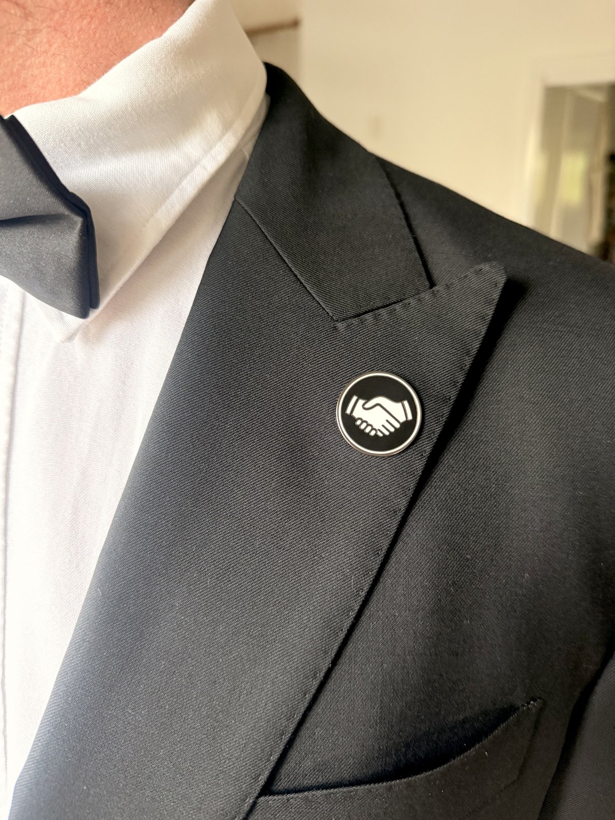 Black Mates pin on a black suit lapel