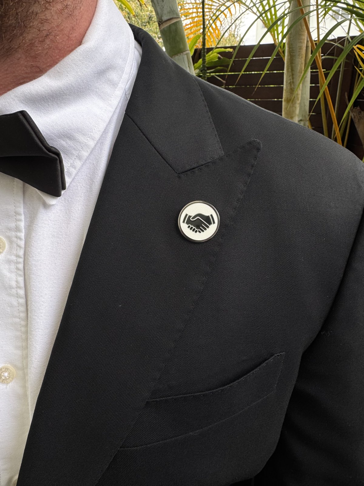 White Mates pin on a black suit lapel with a bow tie
