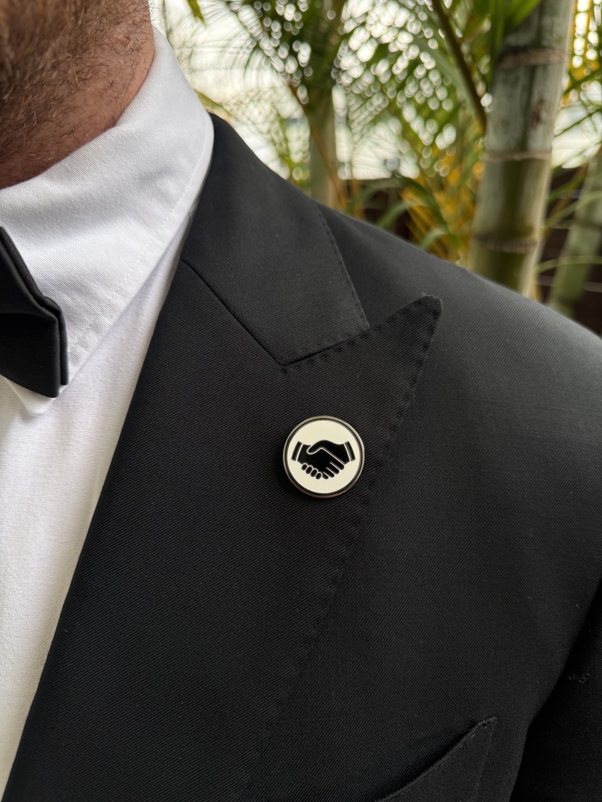 Close up of a white Mates pin on a suit lapel