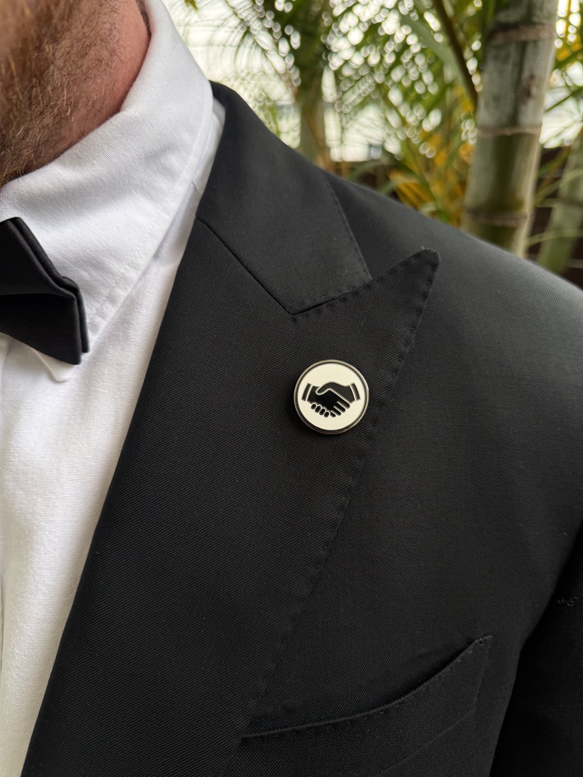 White Mates pin on a lapel, photographed from the side